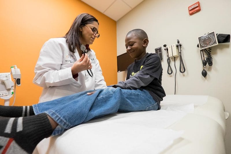 Dr. Mona Hanna-Attisha treats a young patient in a doctor's office.