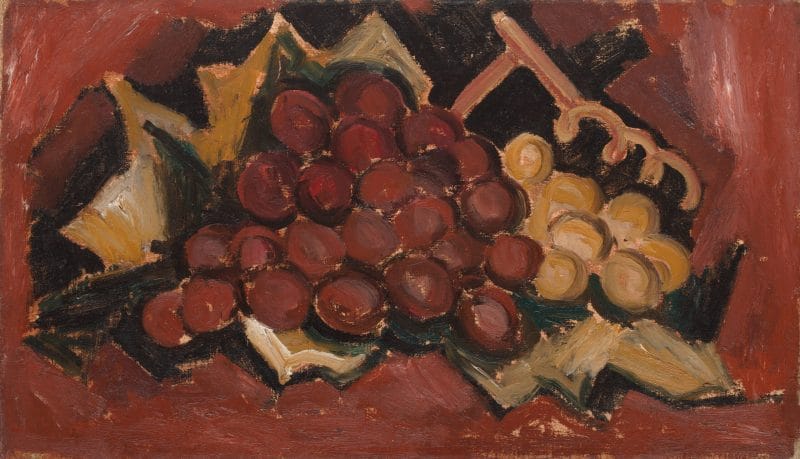 A bunch of red and yellow grapes wrapped in brown paper set against a deep red background.