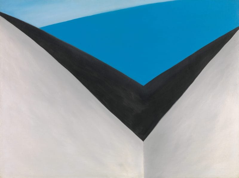 Painted grey and black v-shape structure with a blue sky overhead.