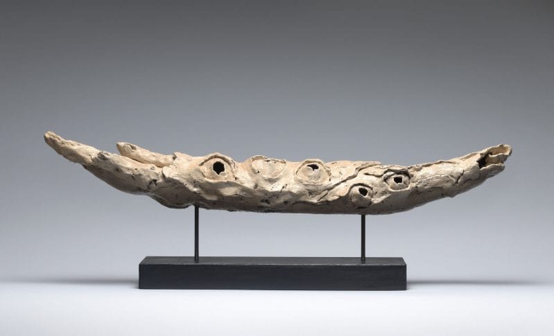 Ceramic beige horn-like horizontal sculpture with holes.