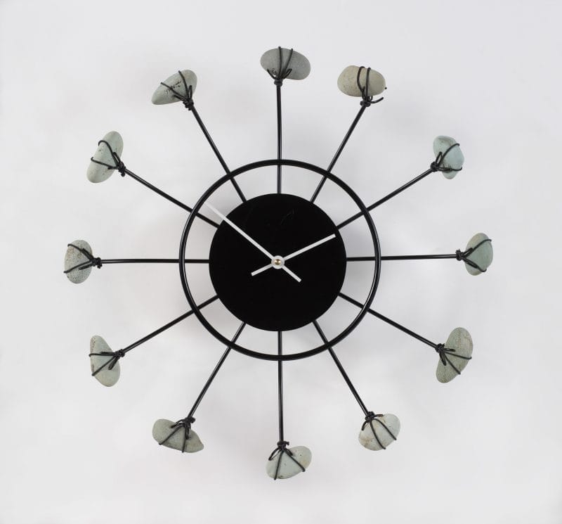 A black metal wall clock with gray stones depicting the hours.