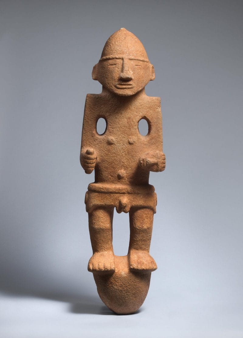 Stone sculpture of a man holding a small head and a tool, wearing a helmet and a belt.
