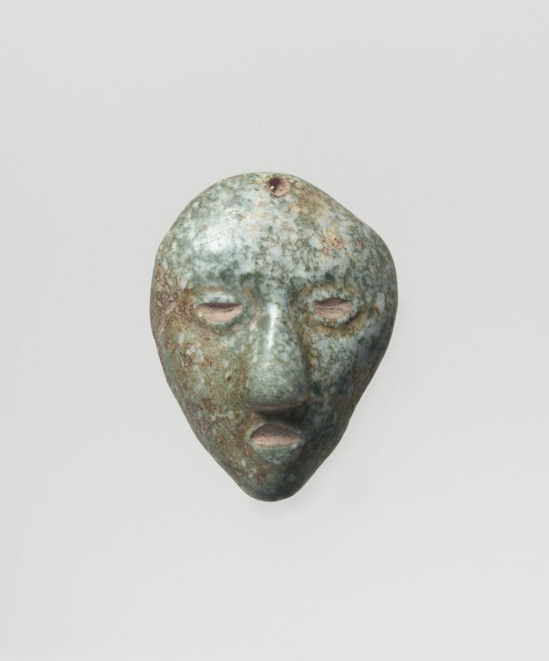 Small stone pendant of a head with an open mouth and large nose.
