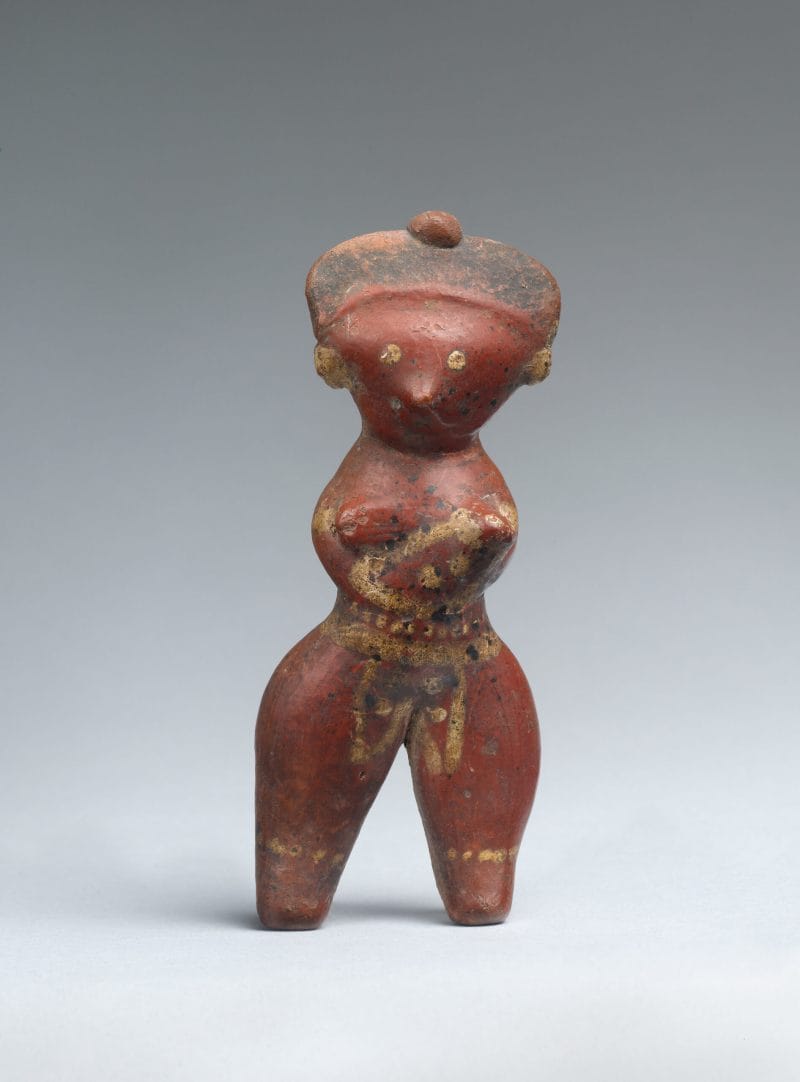 A stylized ceramic standing female figure painted red, yellow, and black.