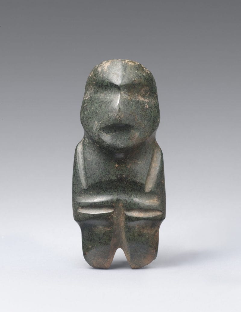 A stylized stone figure with geometric cuts indicating physical features and rounded facial features.