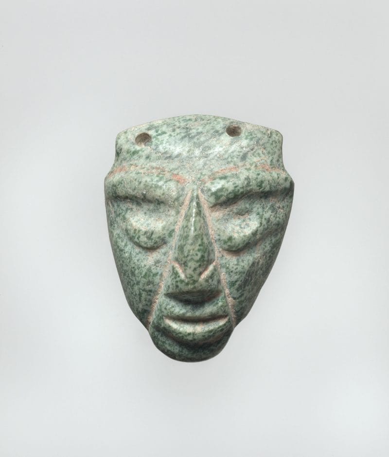 Face pendant with large pointed nose and indented features representing eyes and mouth.