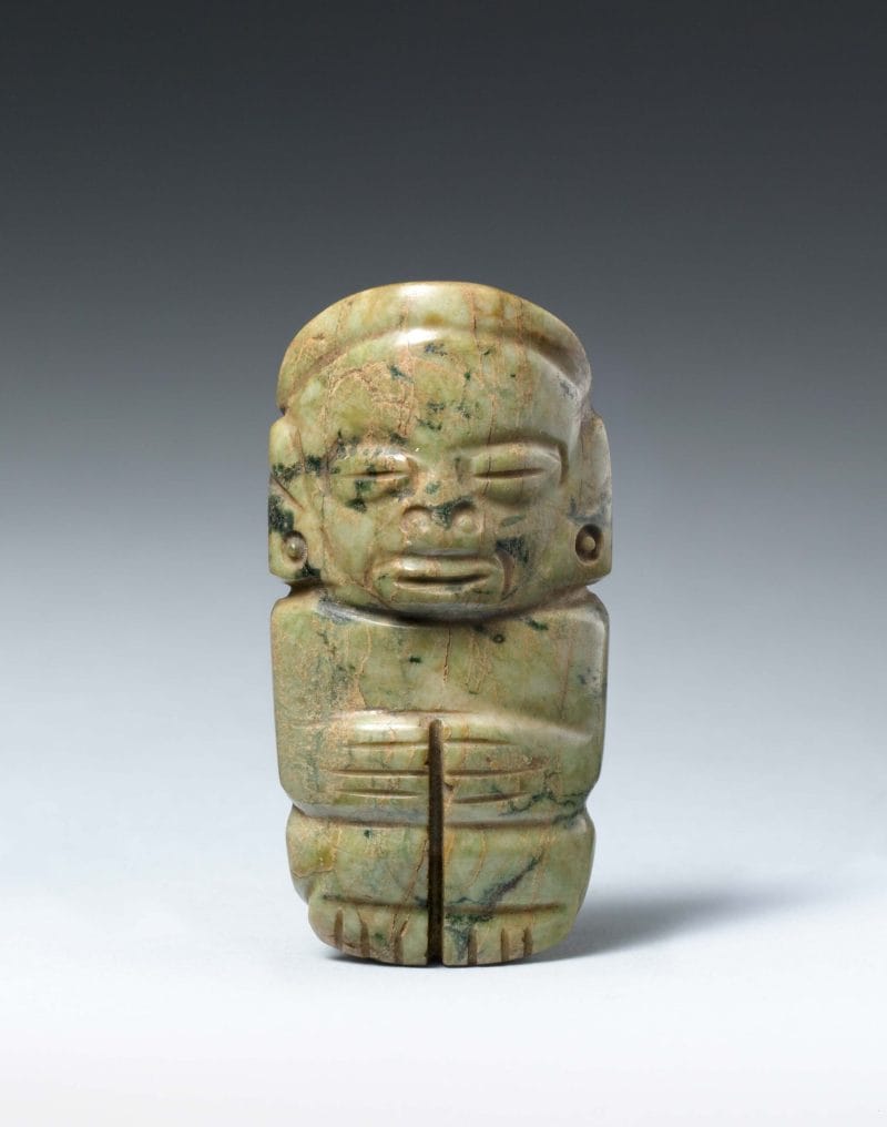 A stylized human figure with facial features carved out, body compressed.