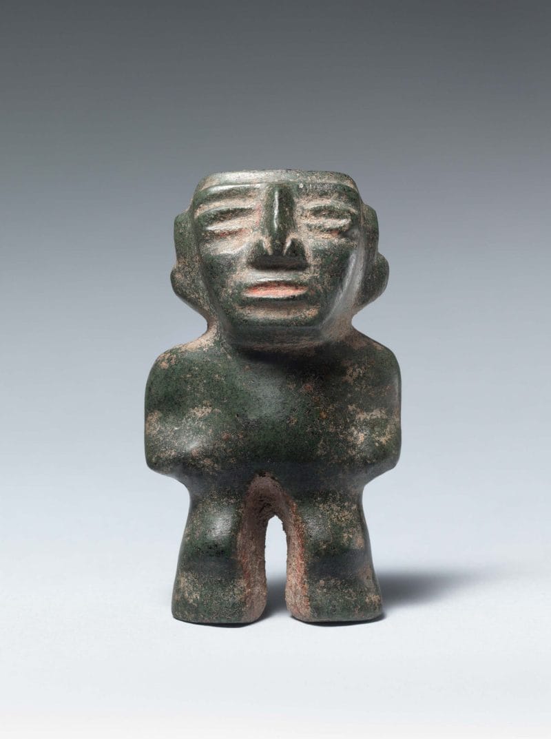 Abstract green stone standing figure with a large pointed nose and indented facial features.