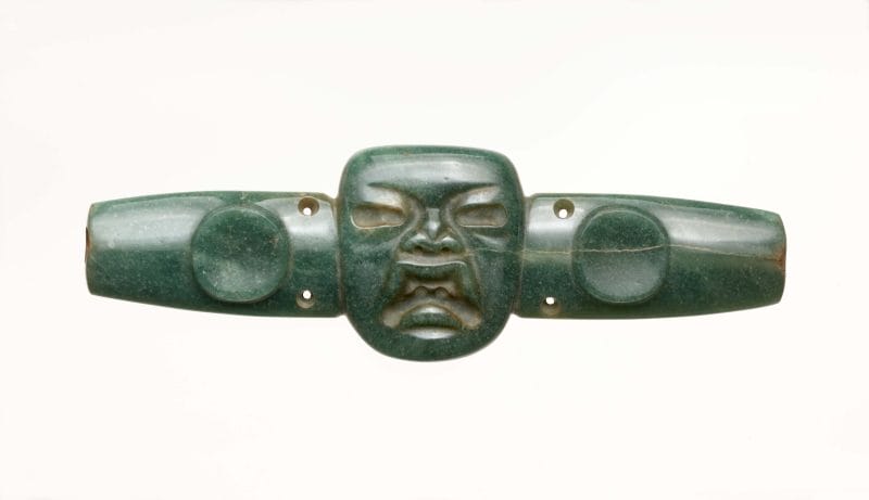 Long, horizontal, blue-green chest ornament with face in relief in center.