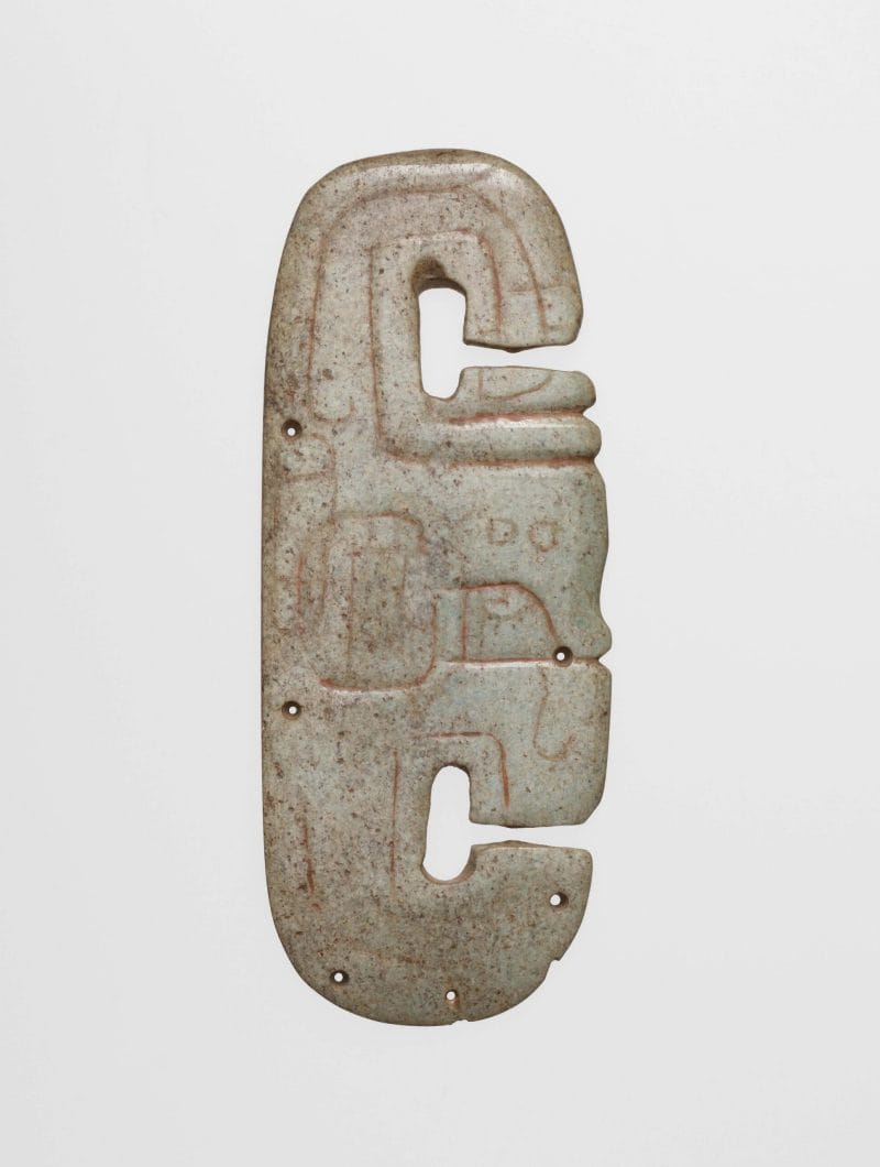 Light green incised stone, C-shaped on either end, with holes around the edge.