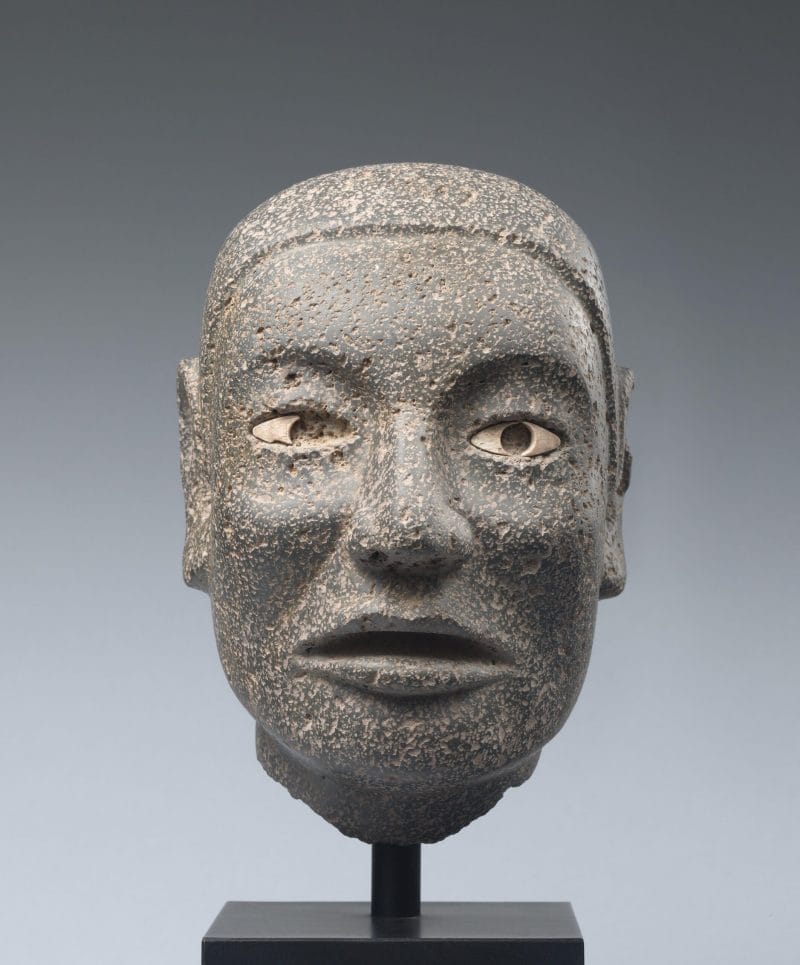 Naturalistic stone carving of a male head with ornamented inlaid eyes.