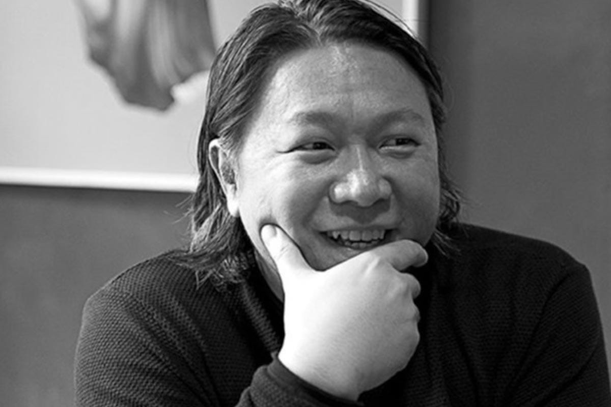 A black and white photo Ham Tran in front of a framed artwork.