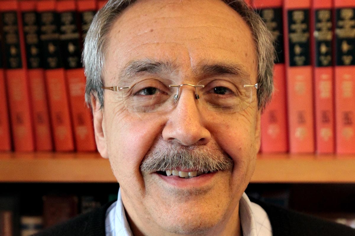 A photo of Carlos Bustamante in front of a library shelf of scientific journals.