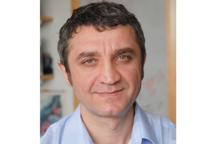 A photo of Ruslan Medzhitov, wearing a blue dress shirt, in his lab.