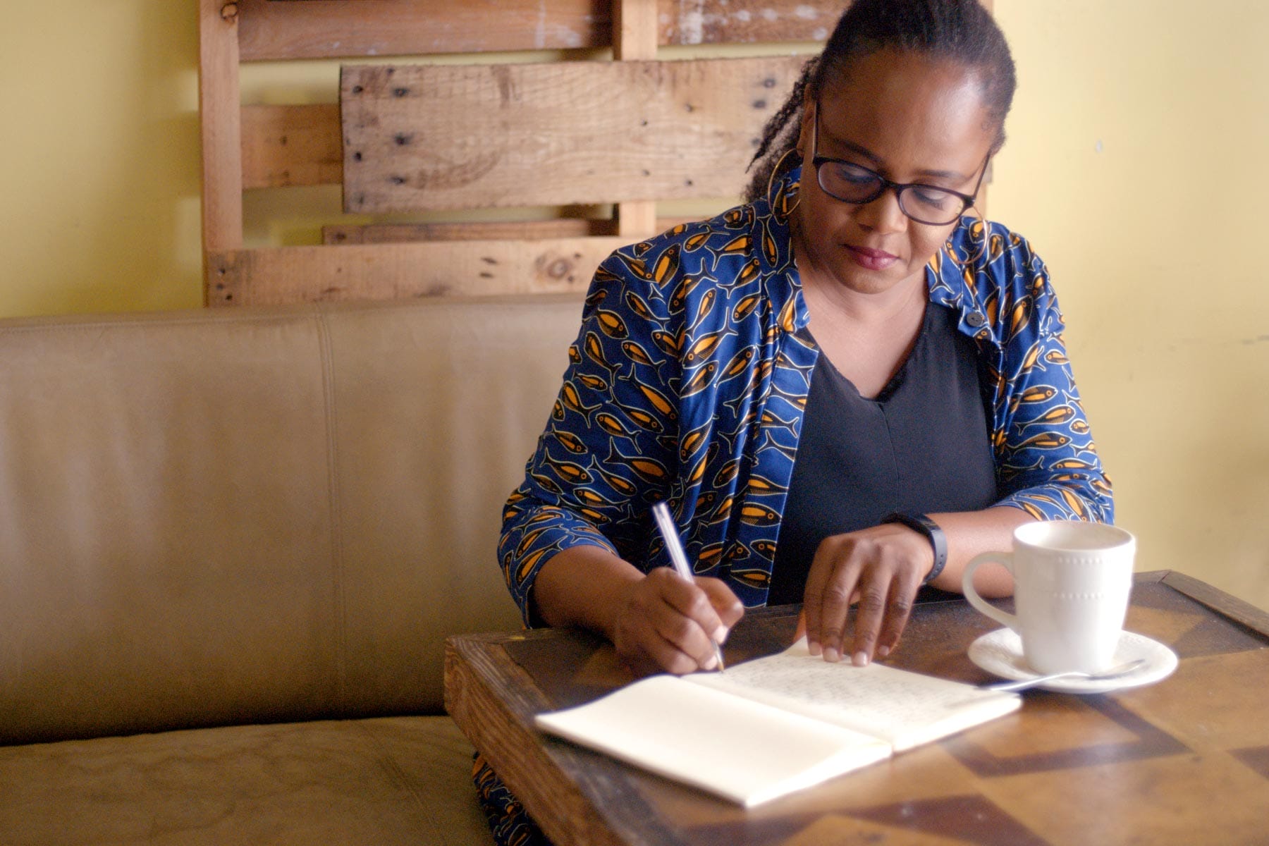 Edwidge Danticat writing in a notebook at a cafe.