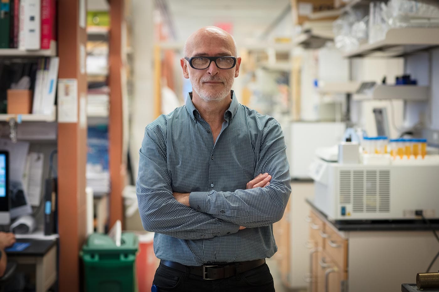 Alexander Rudensky stands in an aisle in his lab with his arms folded.