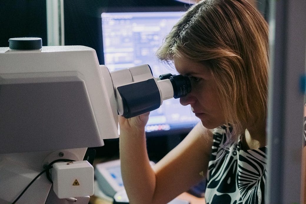 Viviana Gradinaru looking through a microscope.