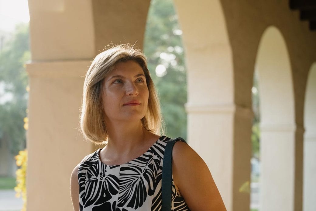 Viviana Gradinaru walking to her lab with Caltech campus' archways behind her.