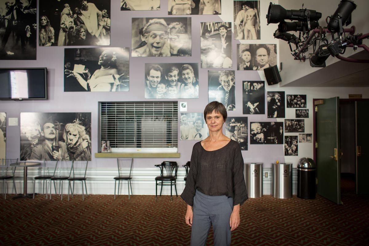 Blanka Zizka is pictured standing in the lobby of a theater, decorated with black and white images of famous actors throughout the ages.