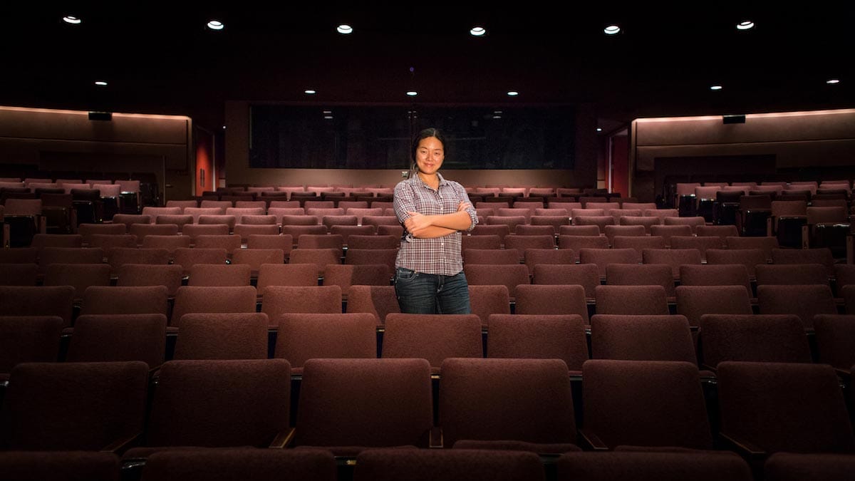 Desdemona Chiang is pictured standing with her arms folded between the rows of seats in the house of a theater.