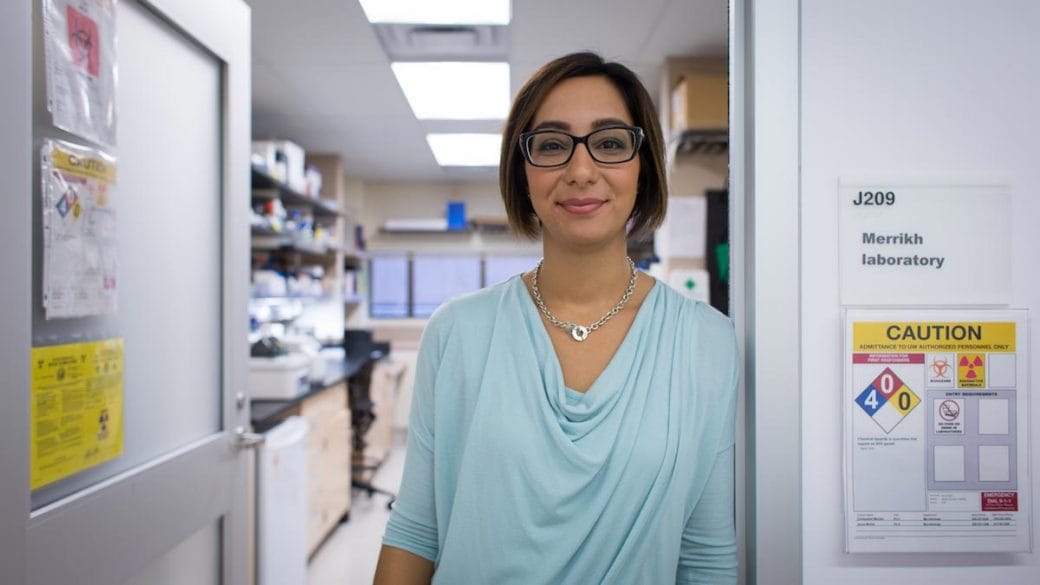 Houra Merrikh is pictured from the waist-up standing in the doorway of her laboratory obscuring the equipment in the background.