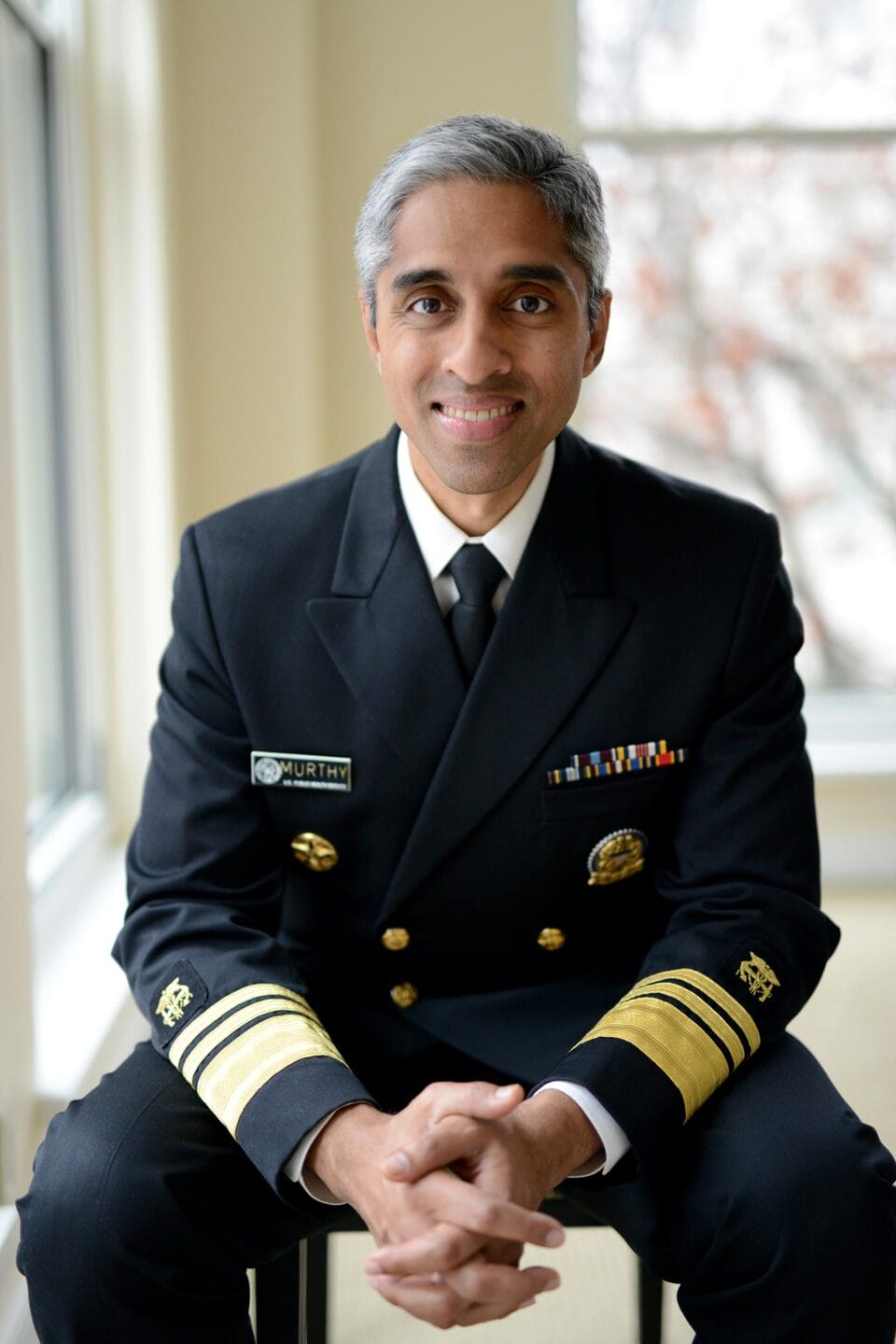 Vivek Murthy sitting on a chair, with collapsed hands, wearing surgeon general uniform.