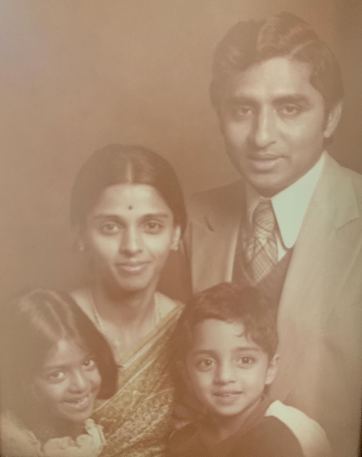 A sepia-tone photograph of Vivek Murthy as a child with his family.