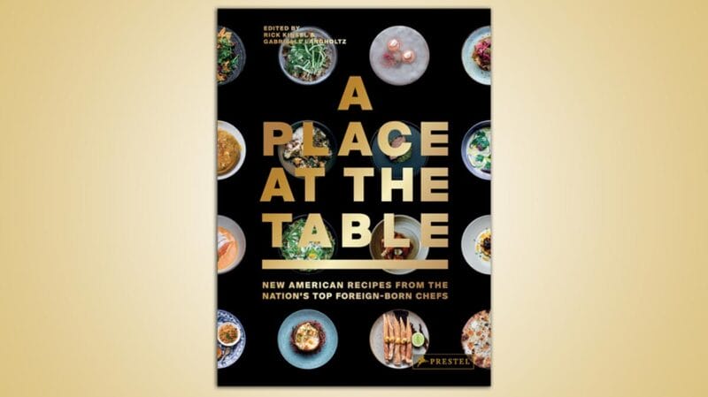 'A Place At The Table' cookbook cover in black and gold.