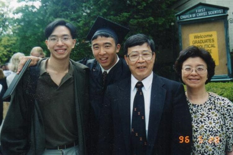 Andrew Yang, in graduation cap and gown, pictured with his brother, father, and mother.