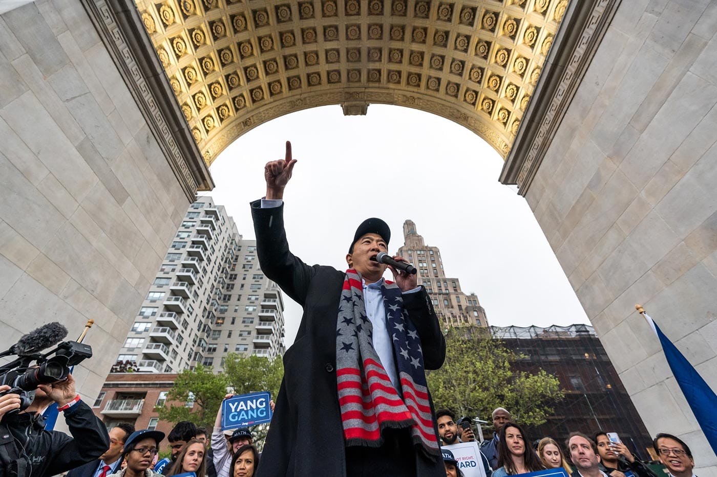 Andrew Yang, campaigning for president, circled by photographers, supporters, and crowds.