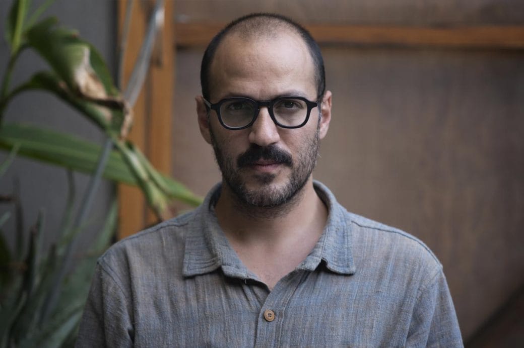 Juan Pablo González in a gray shirt sitting outdoors.