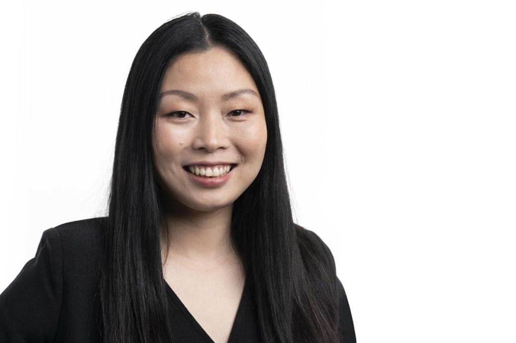 Nanfu Wang, in a black dress, pictured against a neutral white background.