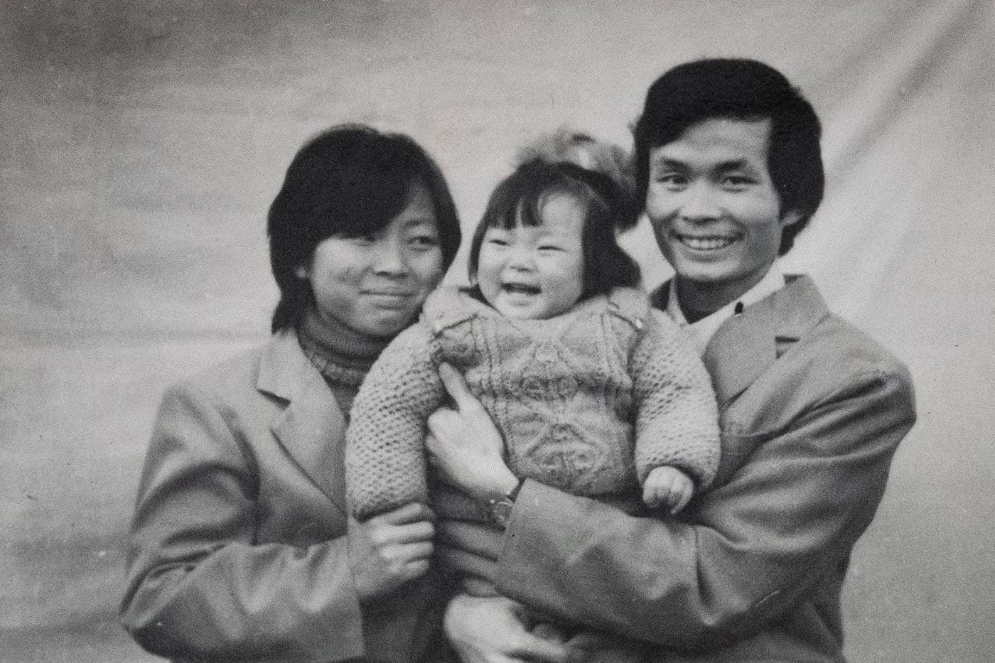Nanfu Wang, at age 1, being held by her mother and father.