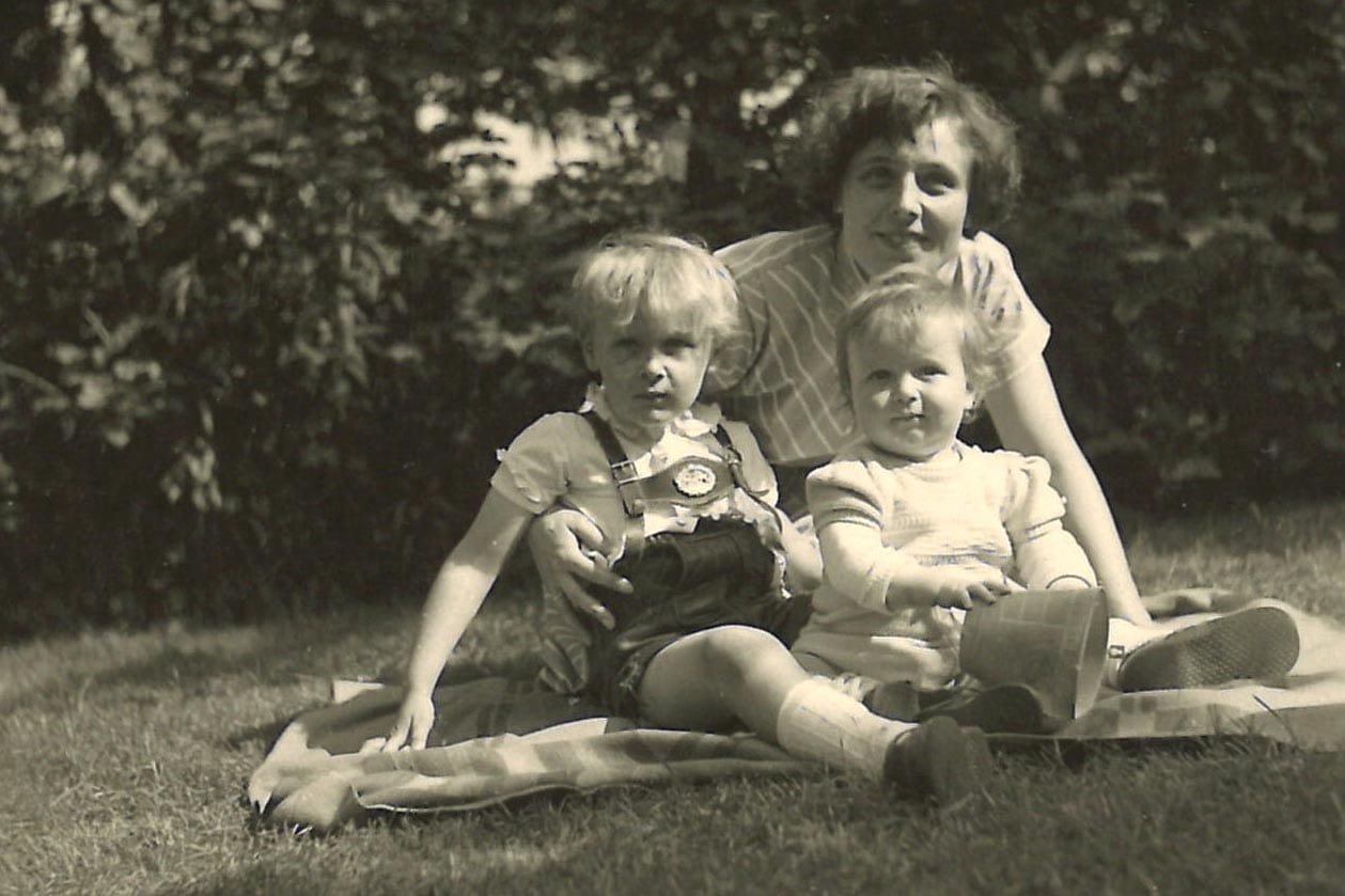 Ruth Lehmann, sitting with her mother and brother on a blanket in the grass.