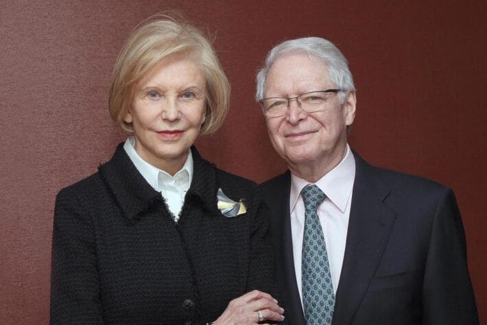 Marica and Jan Vilcek in front of a red wall.