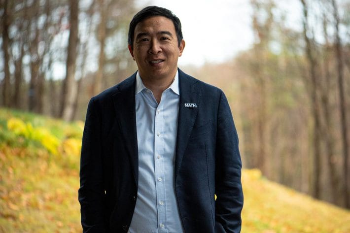 Portrait of Andrew Yang in upstate New York with trees and a hill behind him.