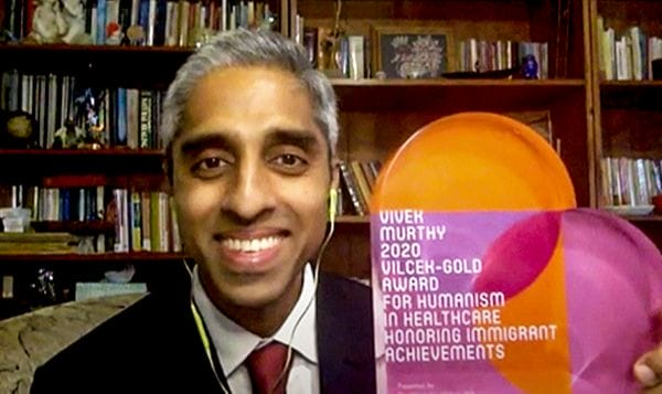 Vivek Murthy holds up the VIlcek-Gold heart-shaped award during an online presentation.