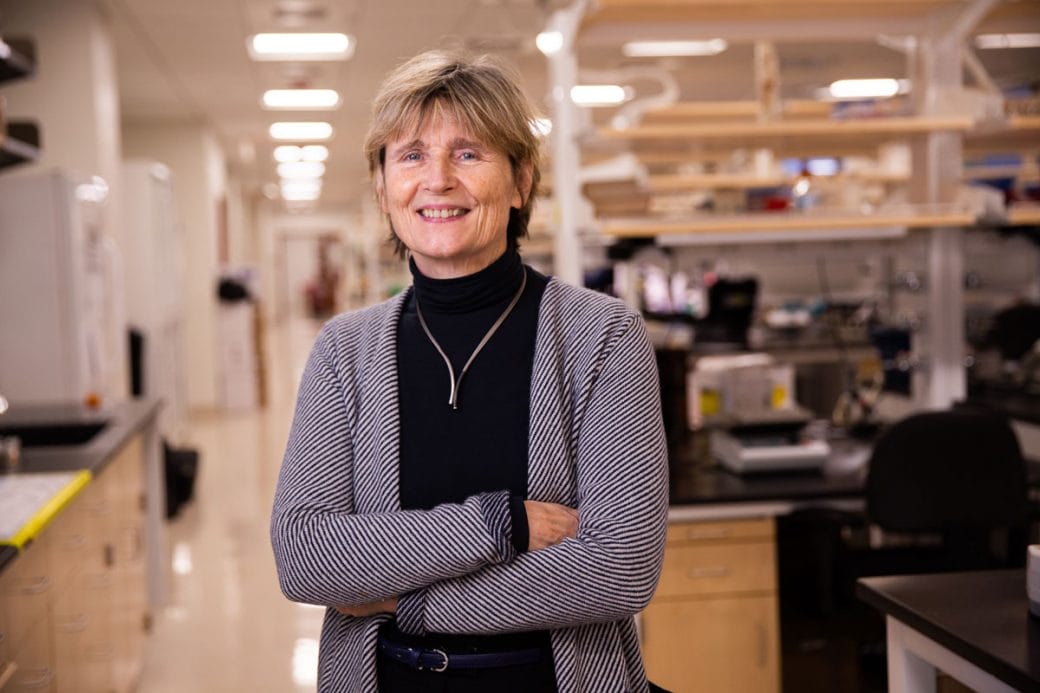 Ruth Lehmann stands in her lab with her arms folded and smiling.