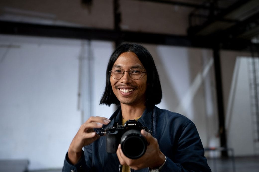 Miko Revereza points his lens towards the camera with a smile on his face.