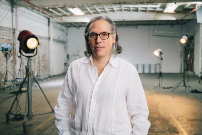 Rodrigo Prieto in a white button-down framed by set lights.