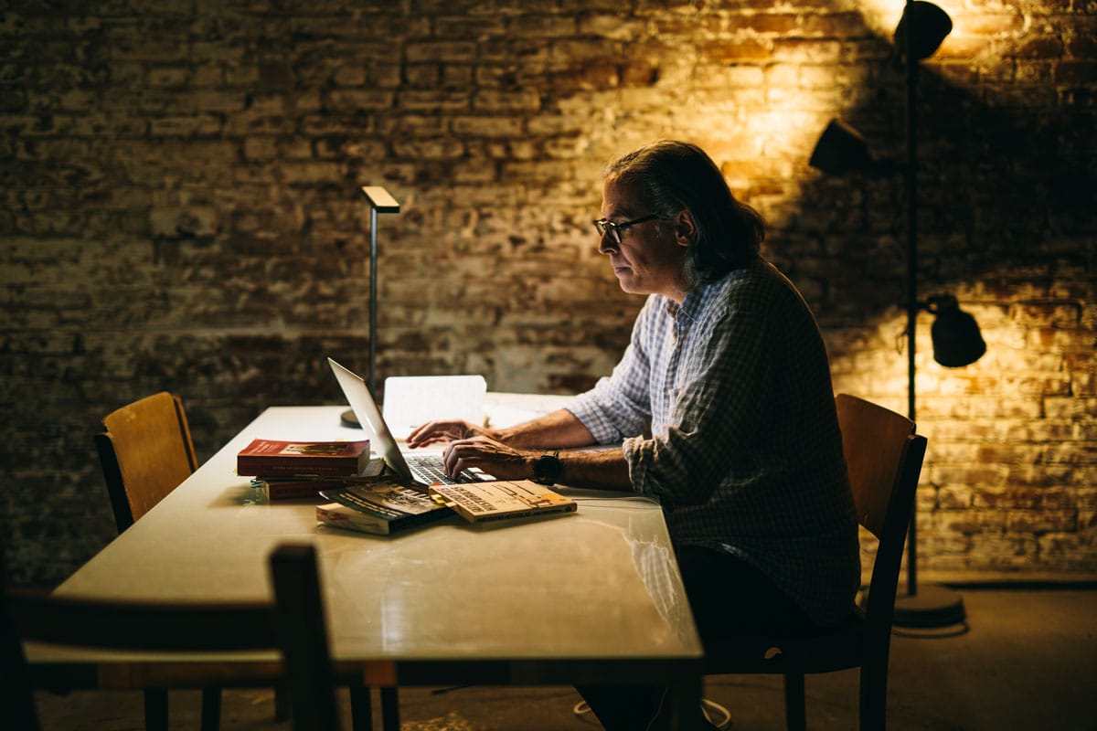 A side profile of Rodrigo Prieto working in lowlight on his laptop.