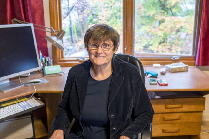 Katalin Karikó sits in her home office dressed in a black blazer.