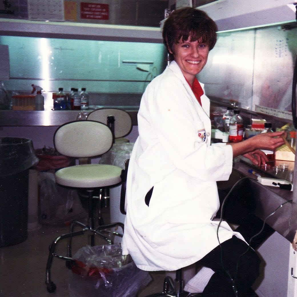 A young Dr. Katalin Karikó smiling in a lab coat.