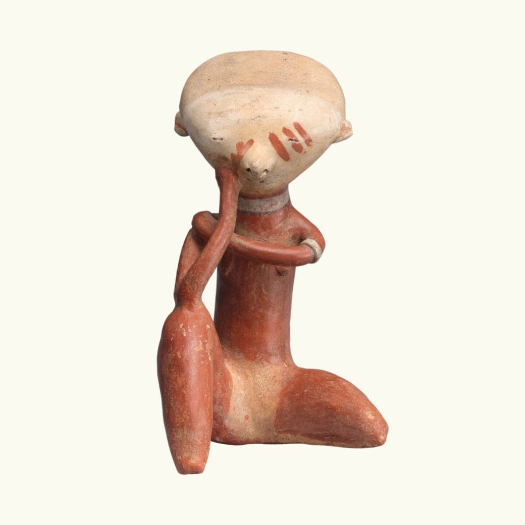 A kneeling ceramic figure in red and beige.