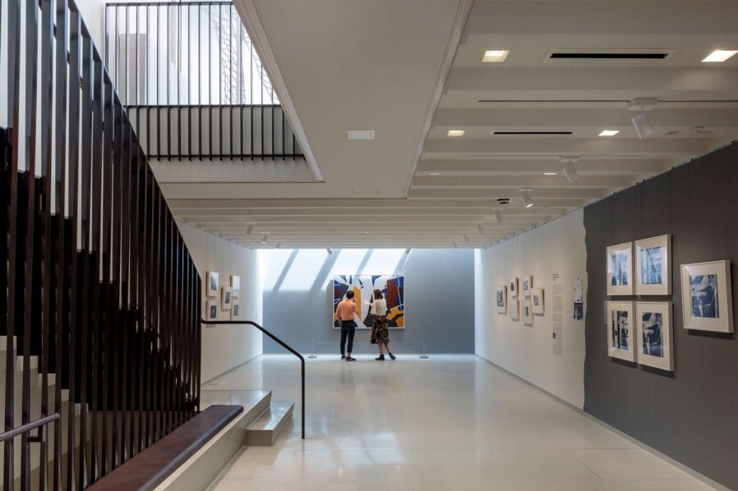 The first floor gallery space of The Vilcek Foundation with a brass staircase and skylight. 