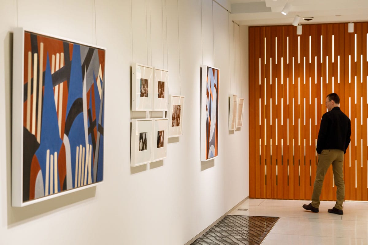 The second floor gallery space with multiple works on the walls, and the decorative wooden exterior of the boardroom. 