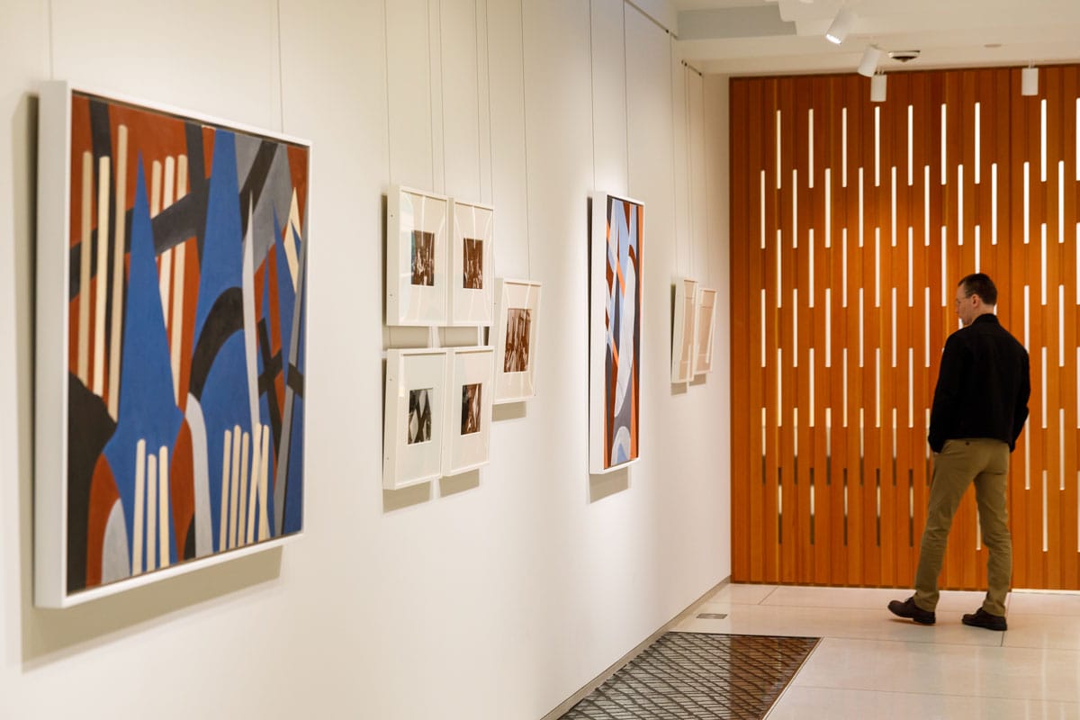 The second floor gallery space with multiple works on the walls, and the decorative wooden exterior of the boardroom.