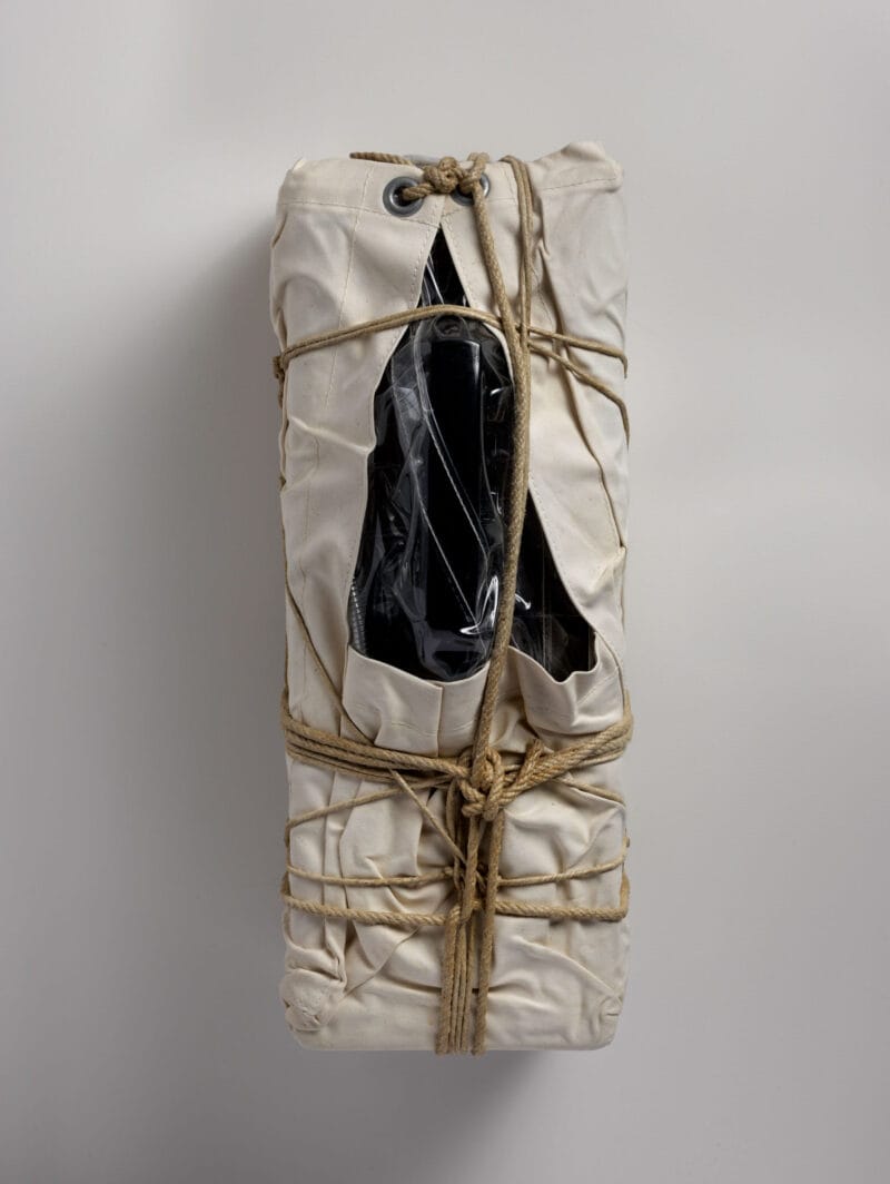 Photograph of a payphone wrapped in sackcloth with rope and twine.