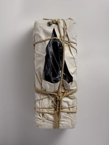Photograph of a payphone wrapped in sackcloth with rope and twine.
