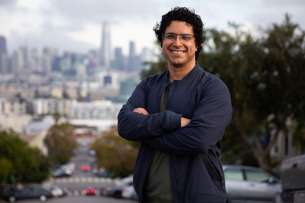 Hani Goodarzi smiles with a cityscape in the background.